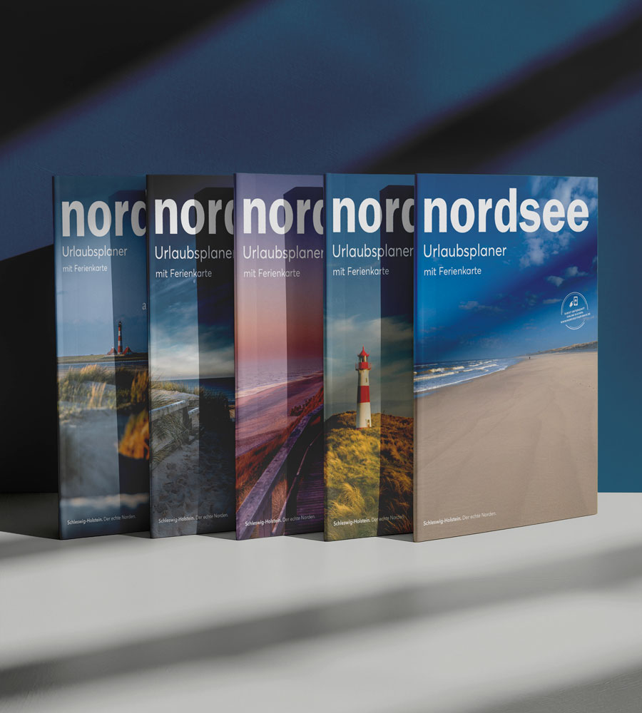 Das aktuellste und die letzten vier Nordsee Urlaubsplaner stehen aufgereiht auf einem Tisch.