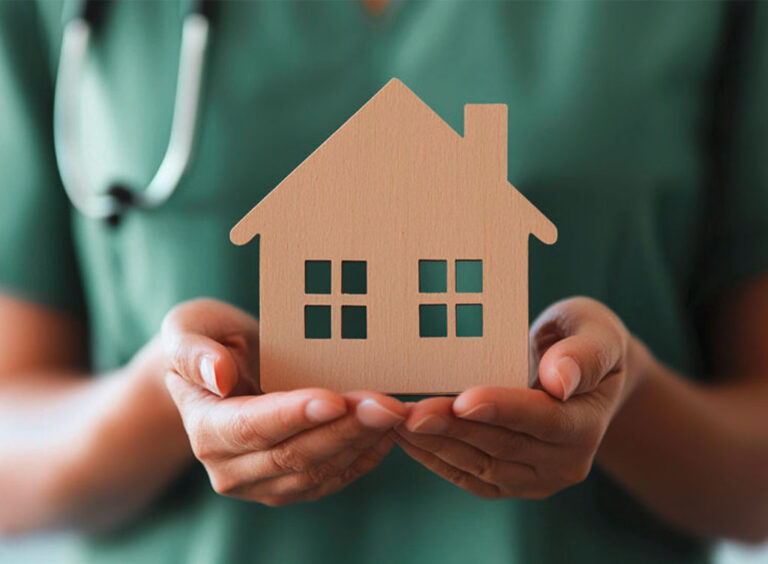 Hände halten ein Holzhäuschen.