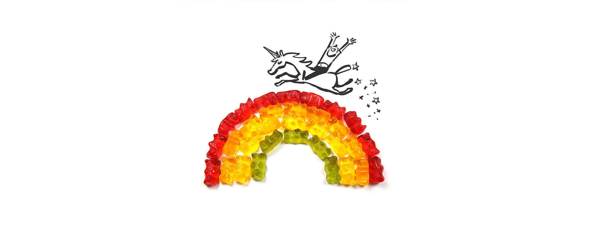 Jemand reitet auf einem Einhorn über einen Regenbogen aus grünen, gelben und roten Gummibärchen.