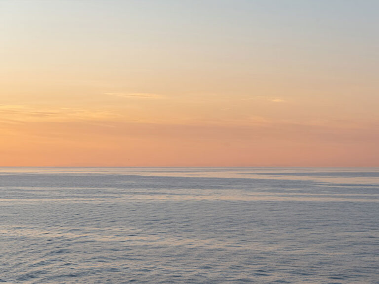 Das ruhige Meer vor einem sanften Himmel.
