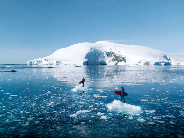 Eine eisige Arktislandschaft mit zwei Personen, die auf Eisschollen stehen.